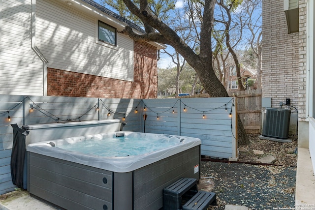 view of yard with central AC unit, fence, and a hot tub