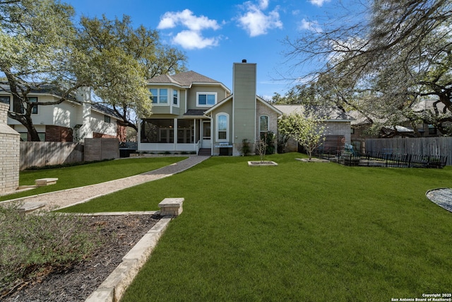 back of house featuring a yard, fence, a sunroom, and a chimney