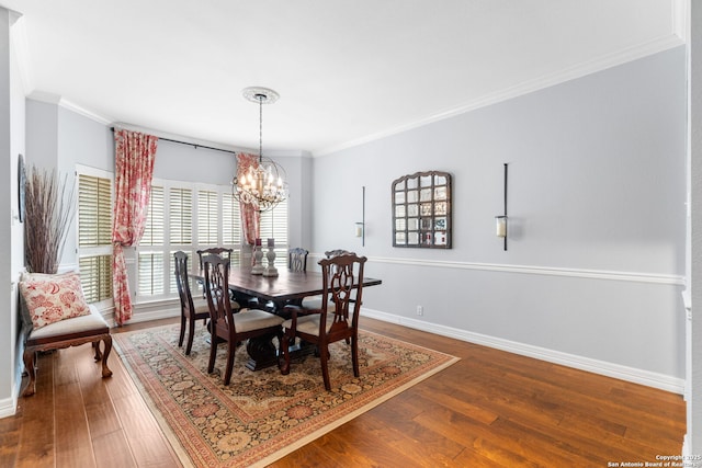 dining space with hardwood / wood-style floors, crown molding, baseboards, and a chandelier