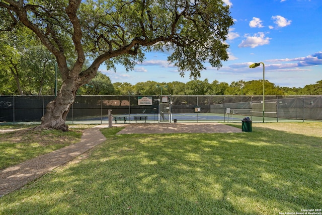 view of sport court with a lawn and fence