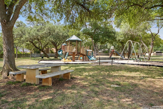 community play area with a lawn and fence