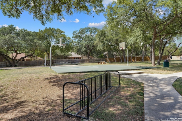 view of community featuring community basketball court, a yard, and fence