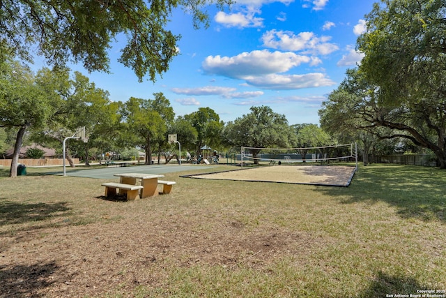 view of community with volleyball court, community basketball court, a yard, and fence