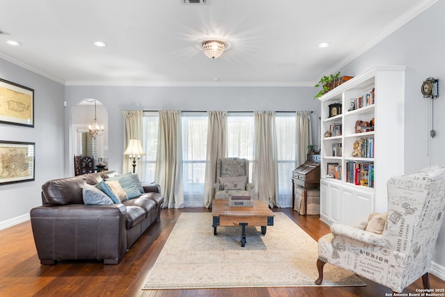 living room featuring dark wood-style floors, arched walkways, an inviting chandelier, crown molding, and baseboards