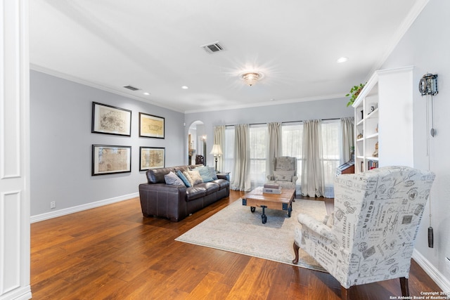 living area featuring baseboards, arched walkways, wood finished floors, and crown molding