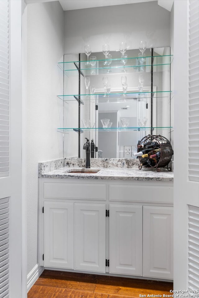 bar featuring indoor wet bar, baseboards, dark wood-style flooring, and a sink