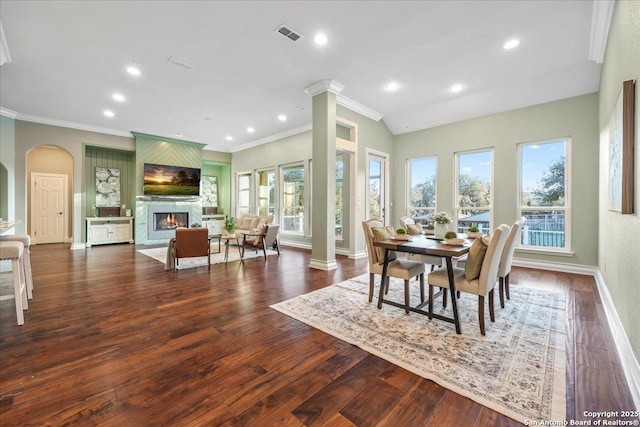 dining space with wood finished floors, decorative columns, a fireplace, and baseboards