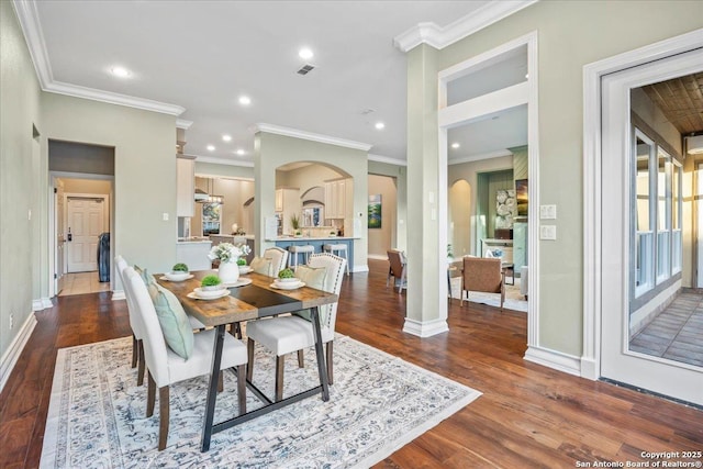 dining room featuring arched walkways, visible vents, baseboards, and wood finished floors