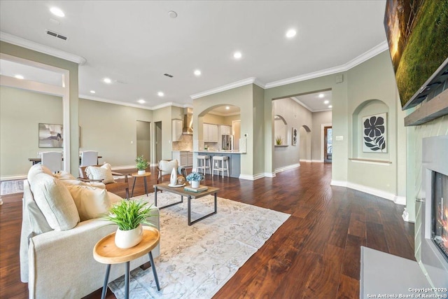 living room with baseboards, visible vents, a fireplace with flush hearth, dark wood-style flooring, and arched walkways