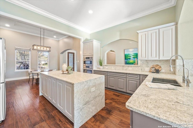 kitchen with a sink, decorative backsplash, a kitchen island, and dark wood finished floors