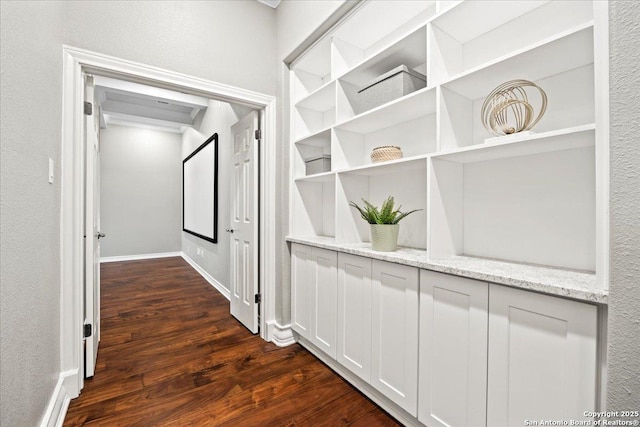 corridor featuring dark wood-type flooring and baseboards