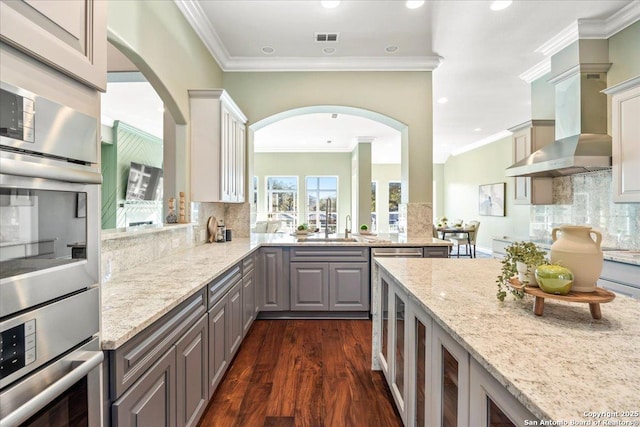 kitchen featuring tasteful backsplash, visible vents, light stone counters, gray cabinets, and wall chimney exhaust hood