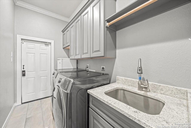 laundry room with a sink, washing machine and dryer, cabinet space, crown molding, and light tile patterned floors