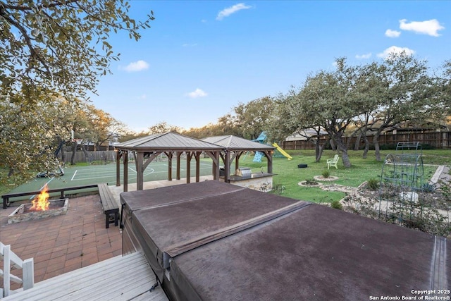 deck featuring a gazebo, a yard, a fire pit, and fence