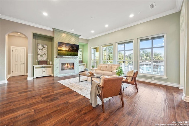 living room with arched walkways, a fireplace, visible vents, and a healthy amount of sunlight