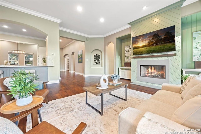 living room featuring arched walkways, a fireplace with flush hearth, recessed lighting, and wood finished floors