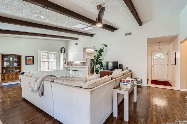 living area with visible vents, a textured ceiling, dark wood-style floors, and a ceiling fan