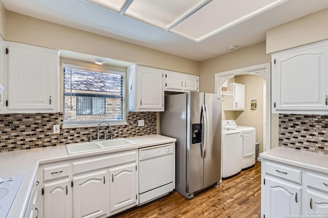 kitchen with a sink, white cabinetry, stainless steel fridge, separate washer and dryer, and white dishwasher