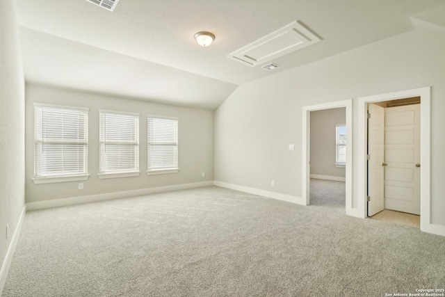 spare room featuring lofted ceiling, visible vents, baseboards, and carpet floors