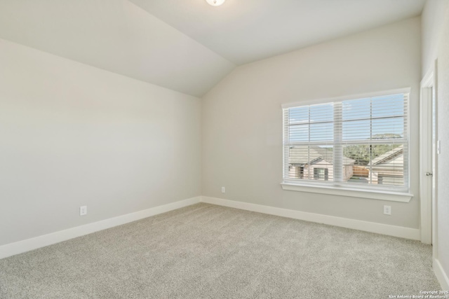 carpeted empty room with lofted ceiling and baseboards