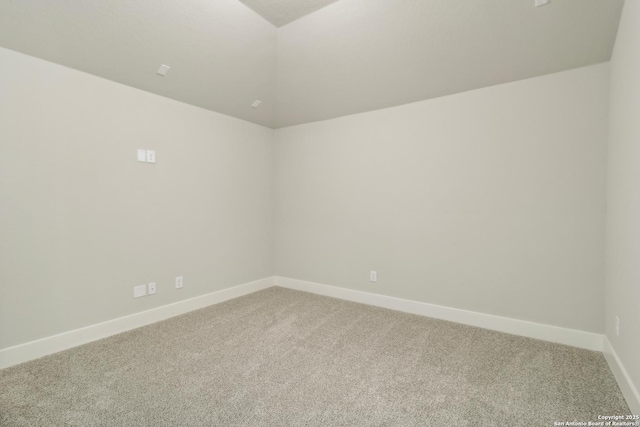 empty room featuring baseboards, lofted ceiling, and light colored carpet