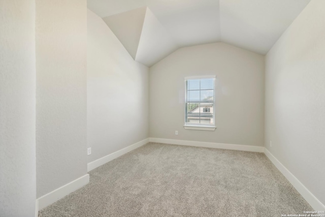 carpeted spare room with lofted ceiling and baseboards