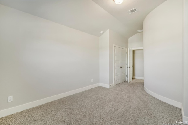 unfurnished room with lofted ceiling, baseboards, visible vents, and light carpet