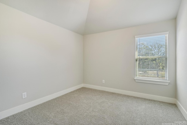 unfurnished room with light colored carpet, baseboards, and vaulted ceiling