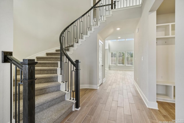 staircase with baseboards, a high ceiling, and wood tiled floor