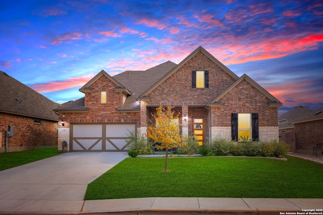 traditional home with a front yard, an attached garage, a shingled roof, concrete driveway, and brick siding