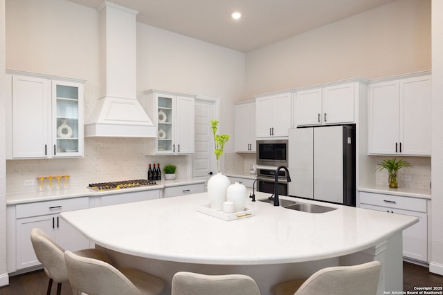 kitchen featuring a center island with sink, a breakfast bar, light countertops, stainless steel appliances, and a sink