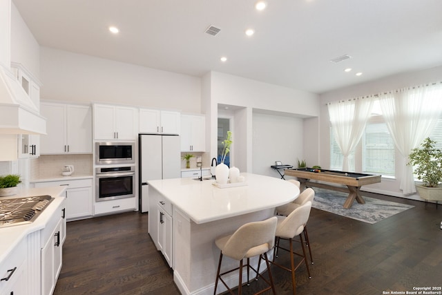 kitchen featuring visible vents, a breakfast bar, light countertops, appliances with stainless steel finishes, and dark wood-style flooring