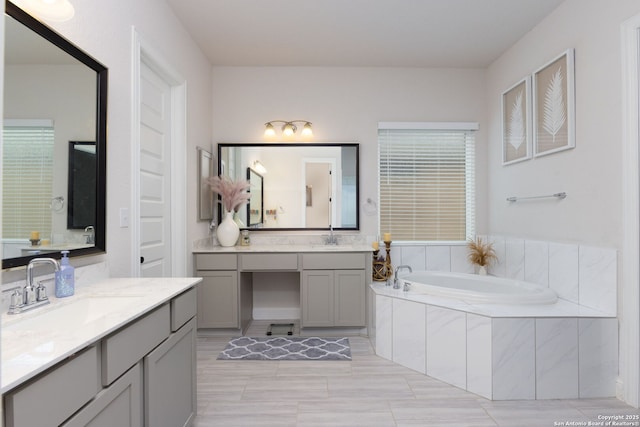 full bath with two vanities, a bath, and a sink