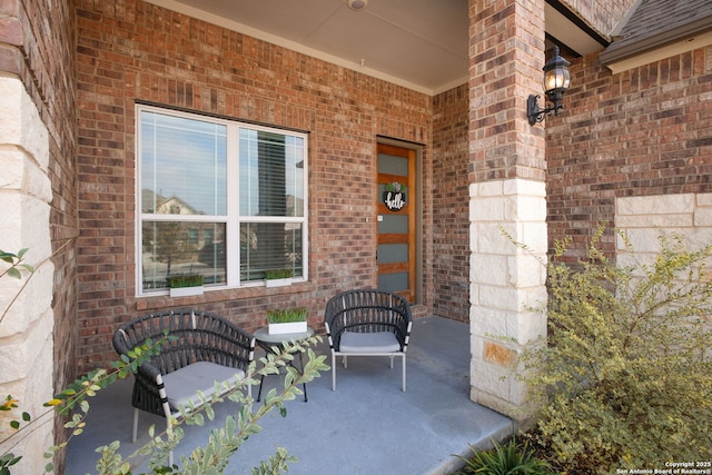 view of exterior entry with brick siding and covered porch