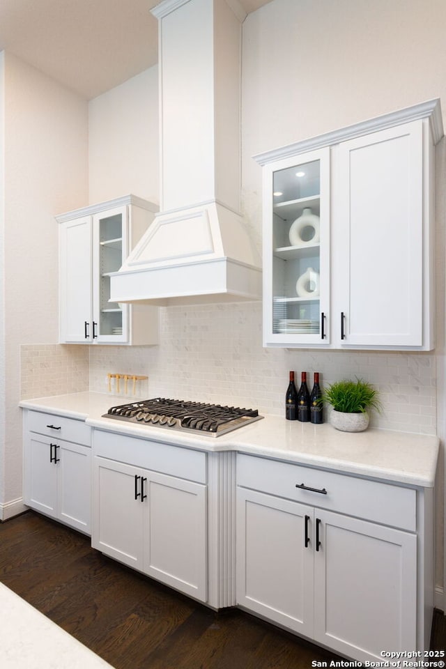 kitchen featuring tasteful backsplash, white cabinetry, light countertops, custom exhaust hood, and stainless steel gas cooktop