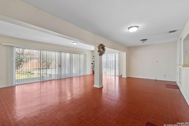 unfurnished room featuring brick floor, visible vents, baseboards, and ornate columns