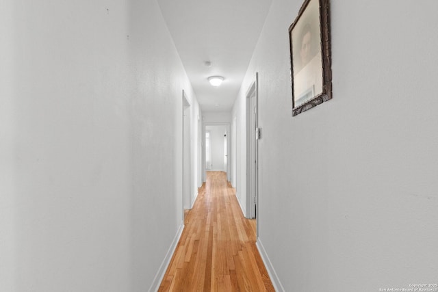 hallway featuring baseboards and light wood finished floors