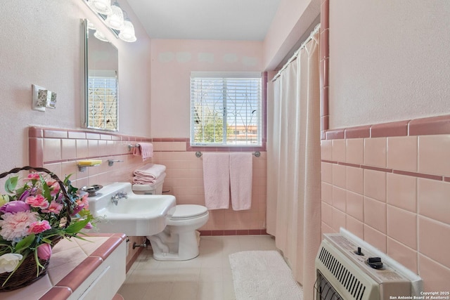 full bathroom with a shower with shower curtain, tile patterned floors, toilet, and tile walls