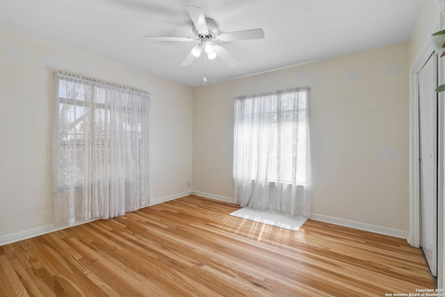 spare room featuring light wood-style flooring, a ceiling fan, and baseboards