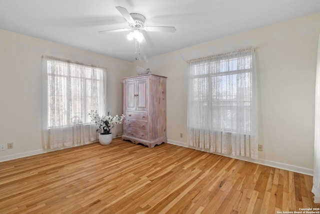 unfurnished bedroom with light wood-style flooring, a ceiling fan, and baseboards