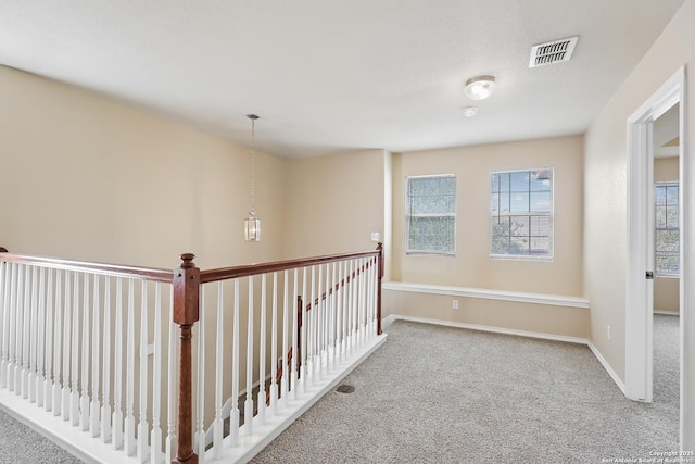 corridor with visible vents, baseboards, and carpet flooring