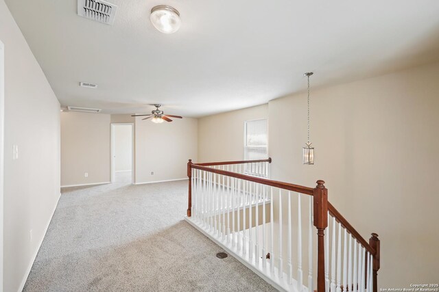 corridor featuring an upstairs landing, visible vents, baseboards, and carpet