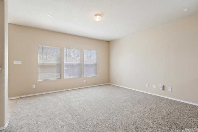 unfurnished room featuring baseboards and light carpet