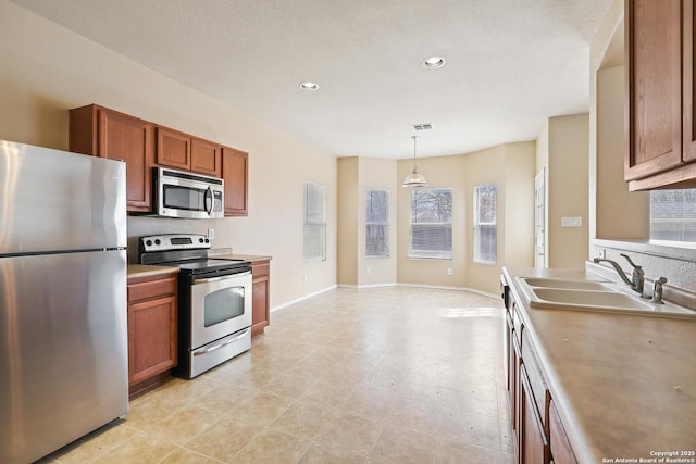 kitchen featuring a wealth of natural light, brown cabinetry, appliances with stainless steel finishes, and a sink