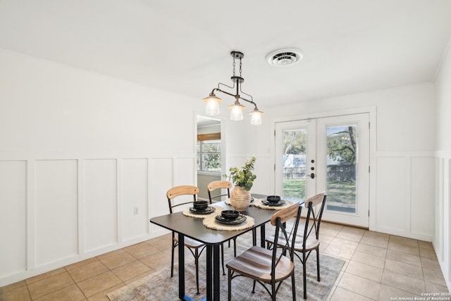 dining space with light tile patterned floors, a decorative wall, french doors, and visible vents