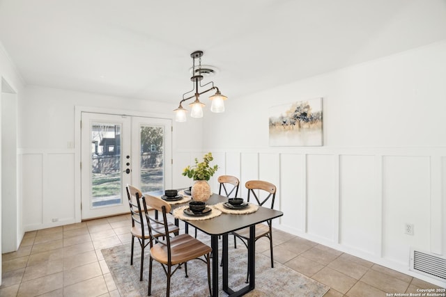 dining area featuring a decorative wall, light tile patterned flooring, french doors, and visible vents