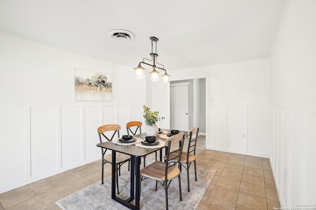 dining area with visible vents, a wainscoted wall, light tile patterned flooring, and a decorative wall