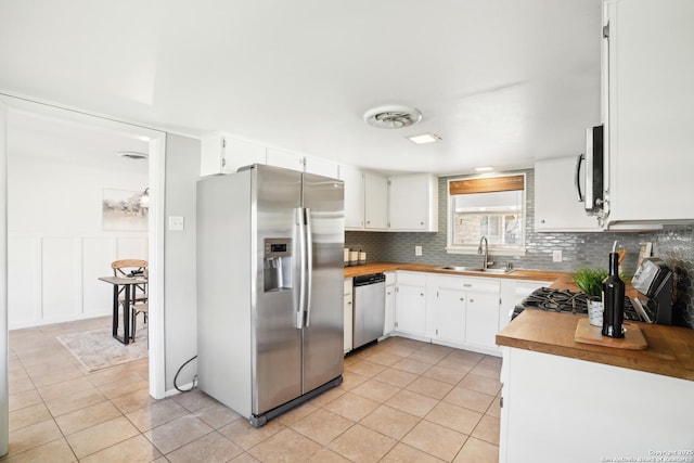 kitchen with visible vents, a sink, appliances with stainless steel finishes, light tile patterned floors, and decorative backsplash