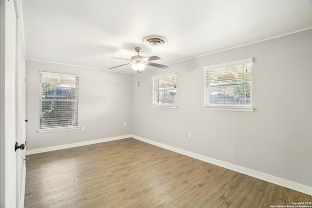 unfurnished room featuring visible vents, ceiling fan, baseboards, ornamental molding, and wood finished floors