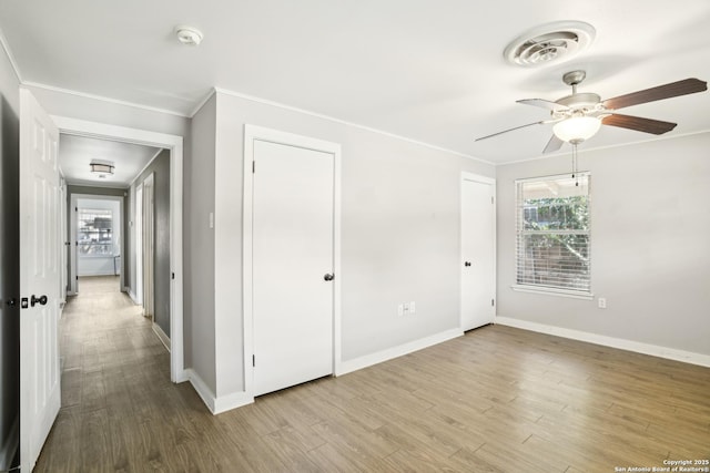 interior space featuring visible vents, ornamental molding, baseboards, and wood finished floors